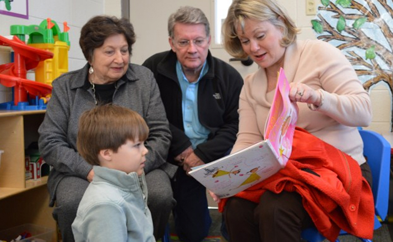 Cardinal Post September 2014: Grandparents reading book to SLS Student.